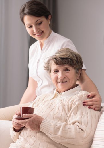 Young female caregiver taking care of older woman